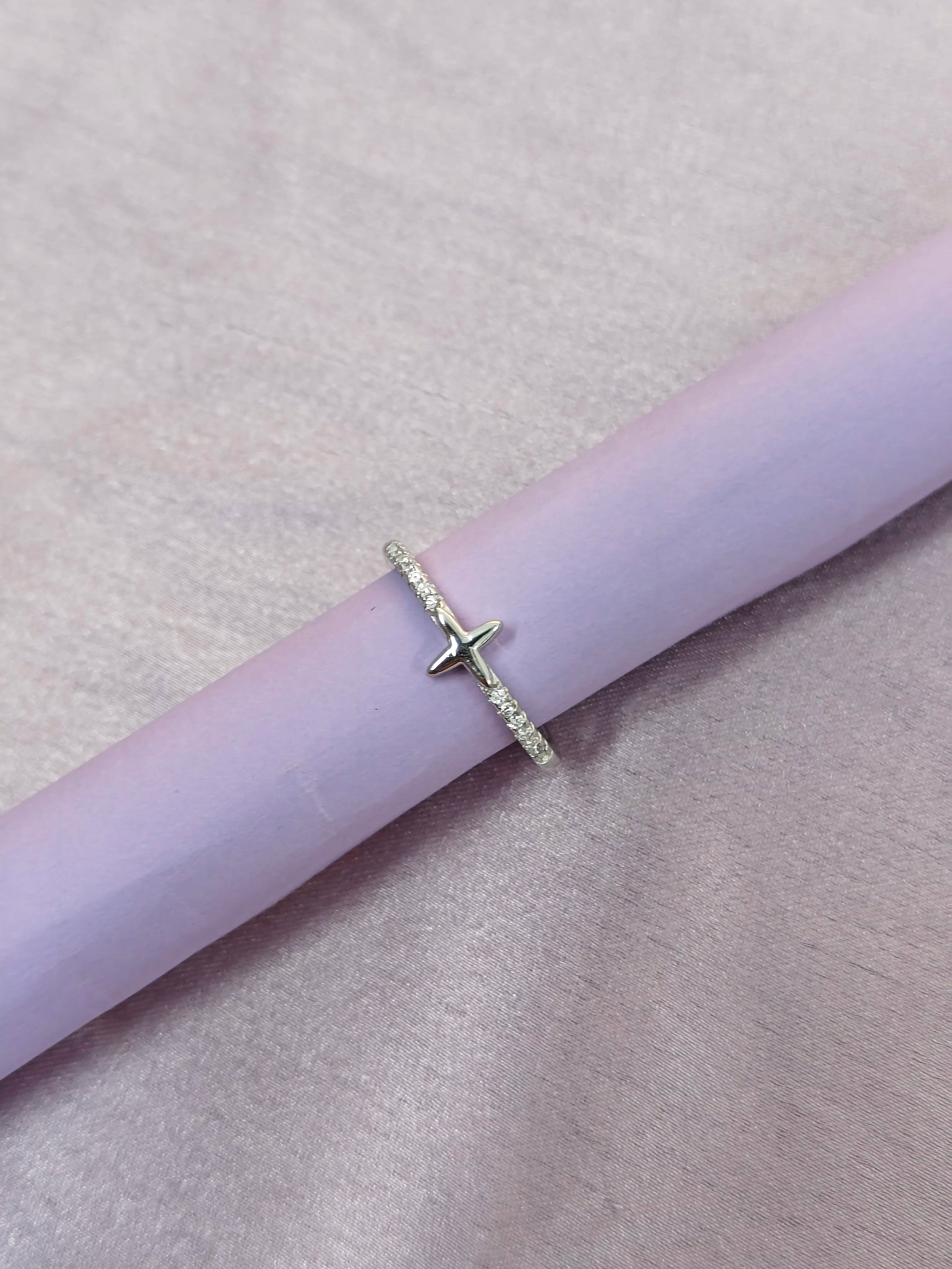 Silver ring with a star design on a pink surface